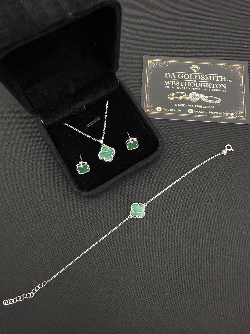 Green pendant, earrings and bracelet displayed on a dark surface